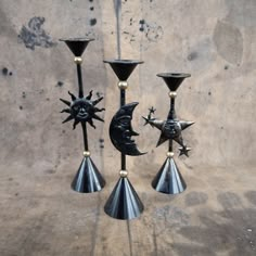 three black candlesticks with sun and moon decorations