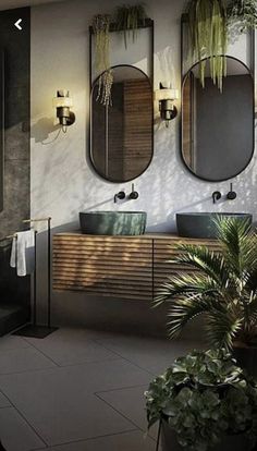 a bathroom with two sinks and three mirrors on the wall next to potted plants