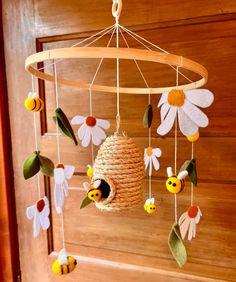 a bee themed mobile hanging from a wooden door with flowers and bees on it's sides