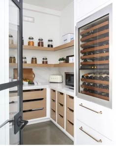 a kitchen filled with lots of wooden shelves and drawers next to an open door that leads into a wine cellar