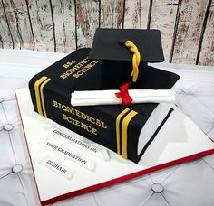 a graduation cake made to look like a book with a mortar and diploma on top