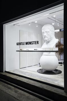 a large white vase sitting in front of a glass window with the words gentle monster on it