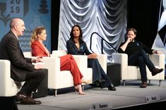 four people sitting on chairs in front of a stage