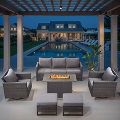 an outdoor living area with couches, chairs and fire pit in the middle of it