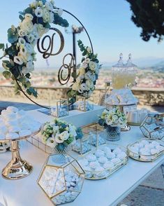 a table topped with lots of desserts on top of a white table cloth covered in flowers