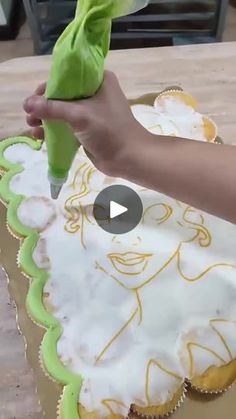 a person is decorating a cake with green frosting and a cloth on it