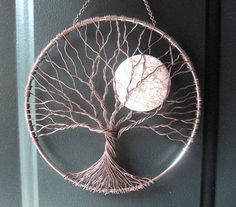 a metal wire tree with a moon hanging from it's center piece on a door