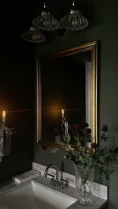 a white sink sitting under a bathroom mirror next to a vase with flowers in it