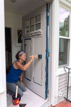 a woman is painting the front door of her house