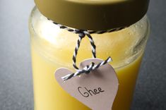 a glass jar filled with yellow liquid and a tag on the lid that says chee