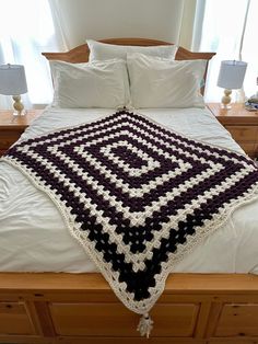 a crocheted blanket on top of a bed in a room with two lamps