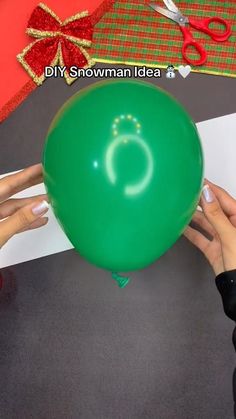 two hands holding a green balloon with the letter o on it and scissors next to it