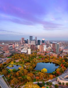 an aerial view of a city with lots of trees in the foreground and a lake in the middle