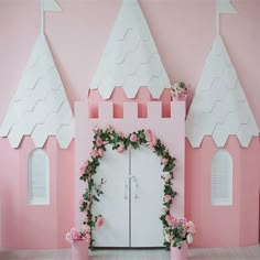 a pink and white castle backdrop with flowers on the front door for a birthday party