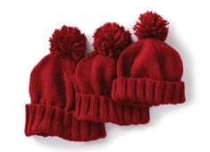 three red knitted beanies with pom - poms on top and bottom