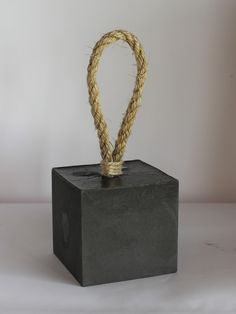 a rope wrapped around the top of a block of black stone on a white background