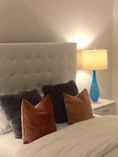 a bed with white linens and orange pillows