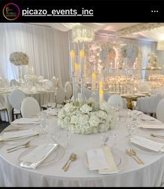 a table set for an event with white flowers and candles