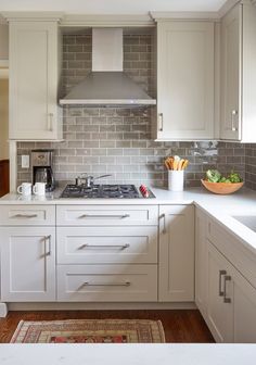 a kitchen with white cabinets and gray tile backsplash