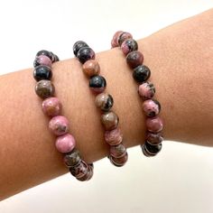 This listing is for one (1) rhodonite bracelet. These are stock photos in which you will be hand selected a bracelet. You will receive one that is similar to the ones pictured.  These are one size: "one size fits all" These are best suited for wrists measuring 5.5-7 inches in circumference. They do stretch quite a bit past that as well (if needed). (I have quite small wrists and they fit me fine, they are not too loose though; my wrists are shown in the picture). They are strung on elastic string in order to fit almost any wrist size!  Chip Style: these are round beads Stone size: 8mm Each order is packaged with love and care. If you have any questions feel free to message me! Rhodonite Bracelet, Gemstone Bracelet, Round Beads, Arm Band, One Pic, One Size Fits All, Jewelry Bracelets, Etsy Accessories, Beaded Bracelets