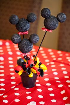 a mickey mouse centerpiece on top of a red table with white polka dot cloth