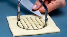 a person using a pair of scissor to cut dough into small balls with white icing