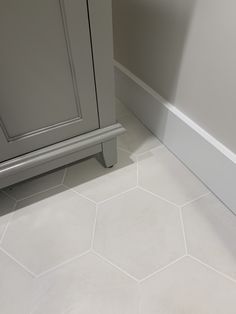 a bathroom with white tile floors and gray cabinetry next to the toilet seat area