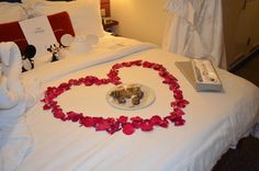 a heart shaped bed with flowers on it and two candles in the shape of hearts