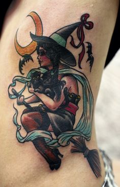 a woman's thigh with a tattoo on it that has an image of a witch holding a cat