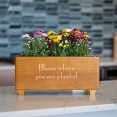 a wooden planter with flowers in it that says, bloom where you are planted