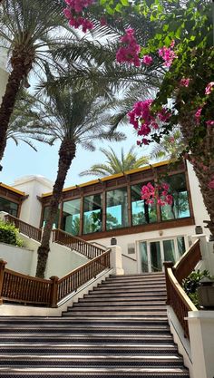 stairs leading up to a building with palm trees and flowers on the steps in front