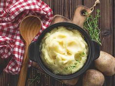 mashed potatoes in a black bowl with a wooden spoon and red checkered napkin