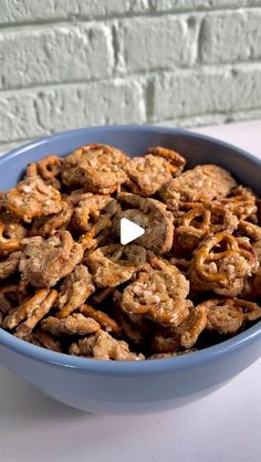 a blue bowl filled with pretzels sitting on top of a white table next to a brick wall