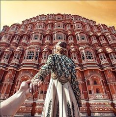 a person holding the hand of another persons hand in front of a large red building