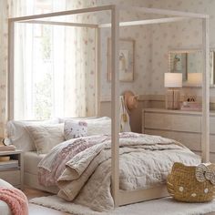 a white bed sitting in a bedroom next to a dresser and window with pink flowers on it