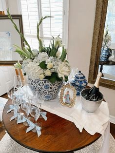 a table topped with vases filled with flowers next to a mirror and framed pictures