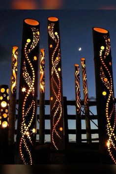 some lights are hanging on poles in front of a fence with the moon behind them