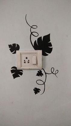 an electrical outlet in the wall with black leaves on it and a light switch cover