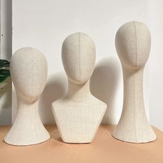 three white mannequins are standing next to each other on a wooden table