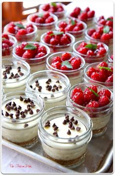 small desserts are arranged in glass bowls on a tray with chocolate chips and strawberries