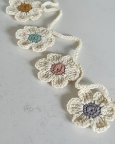 three crocheted flowers on a white counter top with one flower in the center