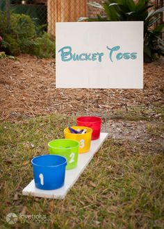 bucket toss game in the yard with colorful cups on it and a sign that says bucket toss