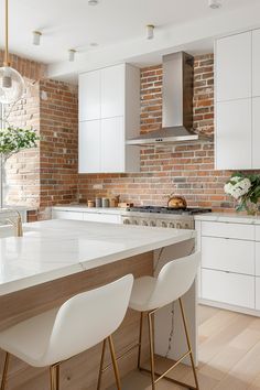 a kitchen with white cabinets and an island in front of a brick wall that matches the ceiling