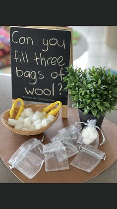 some bags of wool sitting on a table next to a sign and potted plant