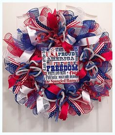 a red, white and blue wreath with words on it hanging on the front door