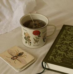 a cup of tea next to a book and coaster