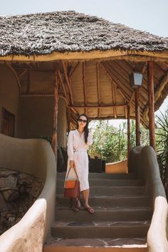 a woman standing on steps in front of a hut