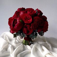 a bouquet of red flowers sitting on top of a white sheet