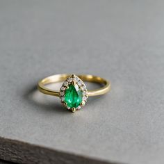 an emerald and diamond ring sitting on top of a table