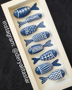 four blue and white ceramic fish in a shadow box on a black wallpapered background